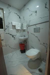 a white bathroom with a toilet and a sink at Hotel Chanda in Jhānsi