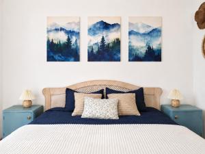 a bedroom with a bed with three paintings on the wall at Blue Cottage in Şpring