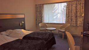 une chambre d'hôtel avec un lit, une table et des chaises dans l'établissement Hotel Falster, à Nykøbing Falster