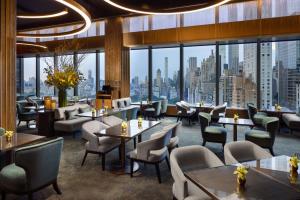 a restaurant with tables and chairs and a view of the city at Mandarin Oriental, New York in New York