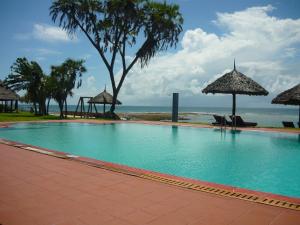 a swimming pool with umbrellas and the ocean at Amani Beach Resort in Dar es Salaam