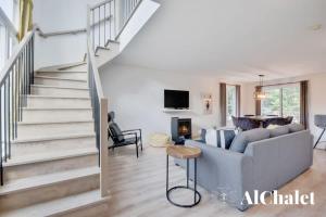 a living room with a couch and a staircase at White Stag - Comfort & Serenity - Sauna & Pool in Pont-Rouge
