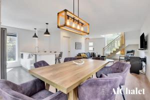 a dining room with a wooden table and purple chairs at White Stag - Comfort & Serenity - Sauna & Pool in Pont-Rouge +20 photos