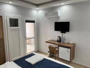 a bedroom with a bed and a desk with a television at Caretta Vita Bella in Silifke