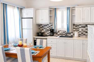 a kitchen with white cabinets and a table with chairs at Villa Oceania in Tourlos
