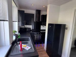 a kitchen with black appliances and a black refrigerator at Bellshill 2 Bed Apartment in Bellshill +13 photos