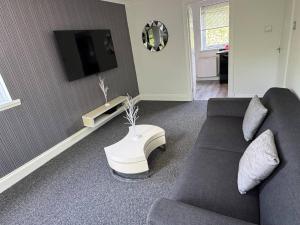 a living room with a couch and a tv at Bellshill 2 Bed Apartment in Bellshill