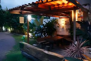 a wooden bench under a pergola with a table at Jungle Beach Maresias in Maresias