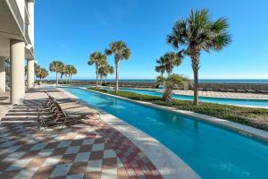 a swimming pool with chairs and palm trees and the ocean at The Oasis 805 in Orange Beach