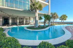 a swimming pool in front of a building with palm trees at The Oasis 805 in Orange Beach