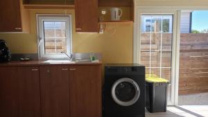 a kitchen with a washing machine next to a window at Bungalow entre oliviers et pins, -10mn de la plage in Châteauneuf-lès-Martigues +12 photos