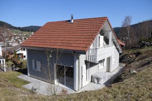 a white house with a red roof on a hill at CHALET AU CALME à GERARDMER in Gérardmer