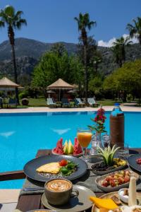 a table with food and drinks next to a pool at Odile Hotel by Naturelife in Cıralı