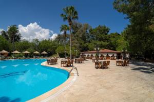 a resort swimming pool with tables and chairs at Odile Hotel by Naturelife in Cıralı