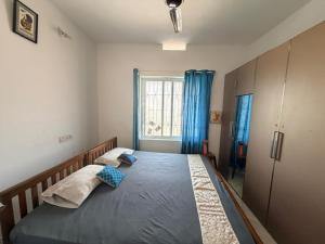 a bedroom with a bed with blue curtains and a window at Ira Wanderlust Homes & Tours in Trichūr