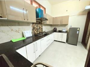 a kitchen with white cabinets and a refrigerator at Kanwar Homestay in Amritsar +9 photos