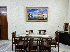 a dining room table with chairs and a picture on the wall at Kanwar Homestay in Amritsar