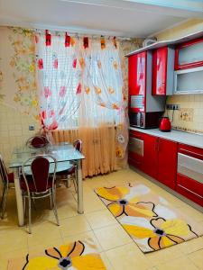 a kitchen with a table and chairs and a kitchen with red cabinets at Two bedroom in Park Zone in Kamianets-Podilskyi