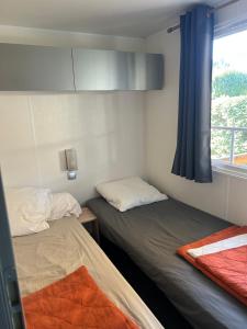 two beds in a small room with a window at Mobil-home Messanges in Messanges