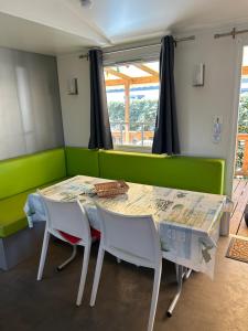 a dining room with a green couch and a table and chairs at Mobil-home Messanges in Messanges