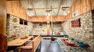 a large room with a table and a stone wall at Tirthan Chalet in Kulu