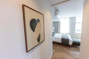 a bedroom with a painting of a hat on the wall at EL HOTEL - The Hague in The Hague