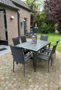a picnic table with chairs and a lantern on a patio at Forest Vacation Home -fenced garden- in Ewijk