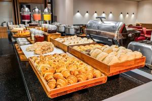a buffet with several trays of bread and pastries at Slim Hotel Campinas in Campinas