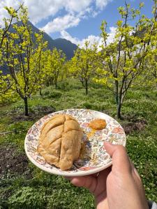 a person holding a plate with a sandwich on it at Tirthan Chalet in Kulu