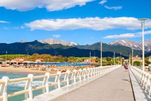 a bridge over a beach with mountains in the background at Villa Alina Family Retreat in Pietrasanta +9 photos
