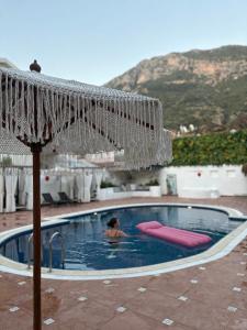 a person in a swimming pool with an umbrella at del Mare Hotel Ölüdeniz in Oludeniz