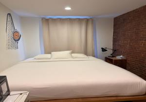 a bedroom with a white bed and a brick wall at Chelsea Rooms NYC in New York