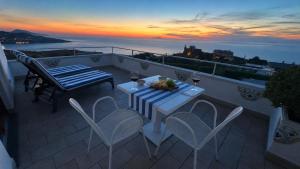 a table and chairs on a balcony with a sunset at Villa Raf in Vico Equense