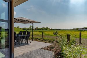a patio with a table and chairs and an umbrella at De Hooiberg in Ritthem