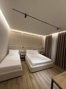 a bedroom with two beds and a table at Hotel Noel in Vlorë