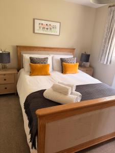 a bedroom with a large bed with orange pillows at Quaker Cottage in Painswick