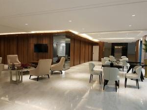 a lobby with white chairs and tables and a television at Itacolomi Hotel in Piçarras