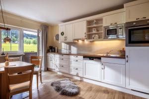 a kitchen with white cabinets and a table and a dining room at Appartement Felsenheim in Westendorf