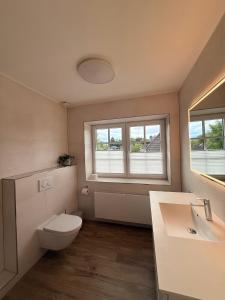 a bathroom with a toilet and a sink and two windows at Ferienwohnung Meeressand in Böhl +28 photos
