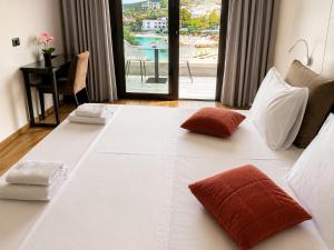 a large white bed with two red pillows on it at Delight Hotel in Ksamil