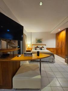 a bedroom with a bed and a desk with a television at Flat na praia da Barra 2 in Rio de Janeiro