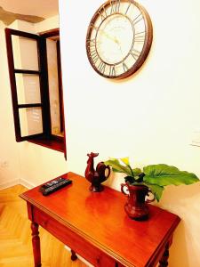 a clock on a wall above a table with a plant at Cozy Central Nest Kotor in Kotor