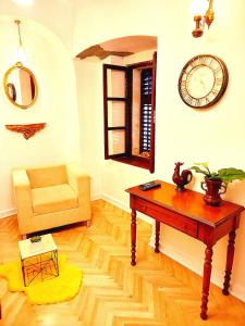 a living room with a table and a chair and a clock at Cozy Central Nest Kotor in Kotor