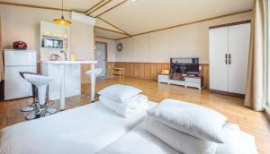 a large room with a white bed and a kitchen at Gurye Jirisan Hosu Resort Pension in Gurye