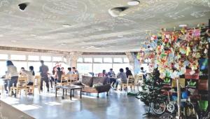 a group of people sitting in a restaurant with a christmas tree at popcorn hostel haeundae in Ch'ŏngsap'o