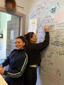 two women standing in front of a wall with writing on it at Gloria Hostel Milano in Milan