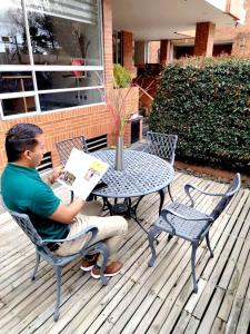 a man sitting at a table reading a book at Prisma Suites Chico 94 in Bogotá
