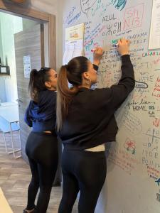 two women standing in front of a wall with writing on it at Gloria Hostel Milano in Milan
