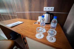 Zwei Wasserflaschen stehen auf einem Holztisch. in der Unterkunft Barkat hôtel in Baraki