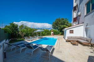 a patio with a pool and chairs and a couch at Moonvidal residence with big private swimming pool and free parking in Pula